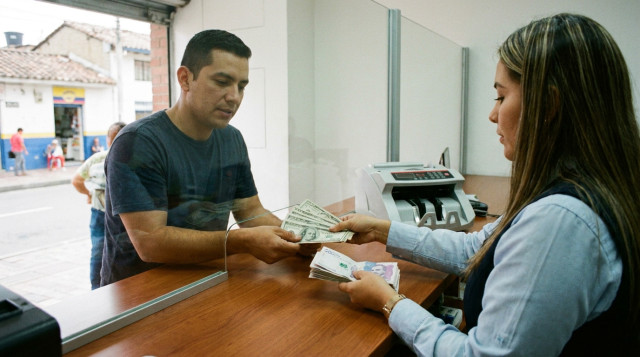 mostrador de una casa de cambio en Colombia con billetes de dólar y pesos, ilustrando el dolar hoy en Colombia