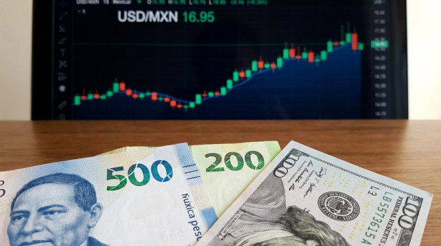 primer plano de billetes de pesos mexicanos y un billete de dólar sobre una mesa, foco en las cifras y una cotización en pantalla de fondo