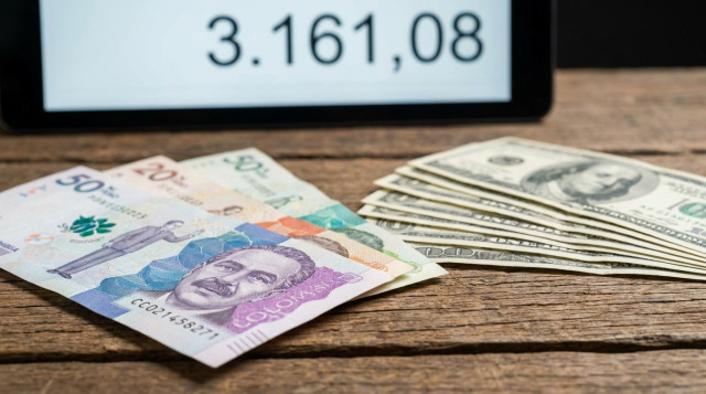 primer plano de billetes de peso colombiano y billetes de dólar sobre una mesa, con una pantalla al fondo mostrando la cifra 3.161,08, composición horizontal, iluminación profesion